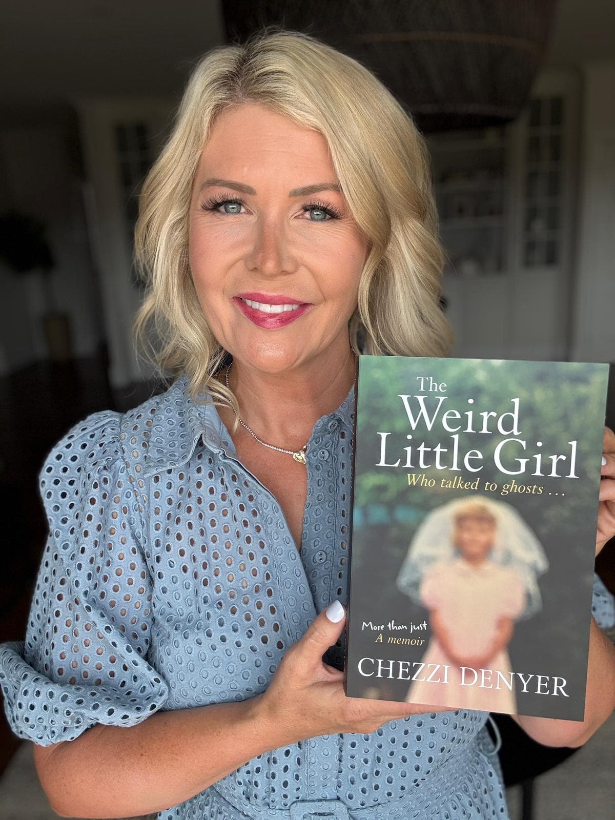 Chezzi holding her bestselling memoir The Weird Little Girl